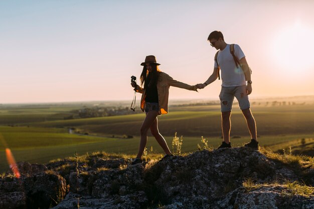 Couple holding hands while hiking on rock