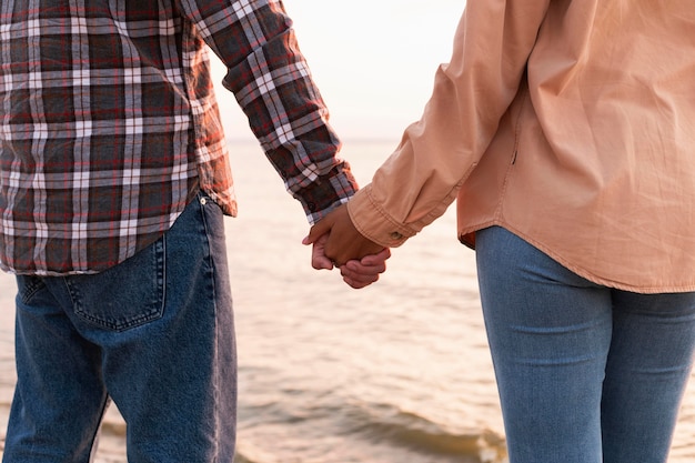 Free photo couple holding hands while taking a walk on the ebach