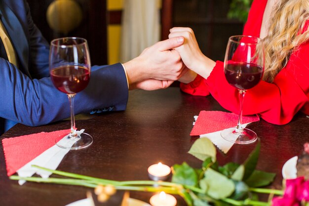 Couple holding hands at wooden table in restaurant 