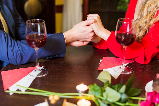 Couple holding hands at wooden table in restaurant 