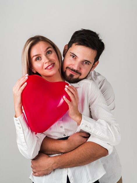Couple holding heart balloon and posing