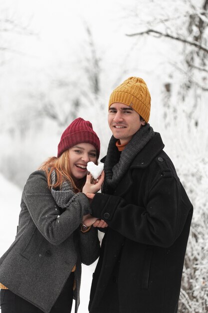 雪から作られたハート形を保持しているカップル