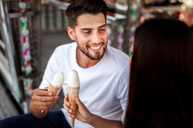 Couple holding ice creams looking at each other