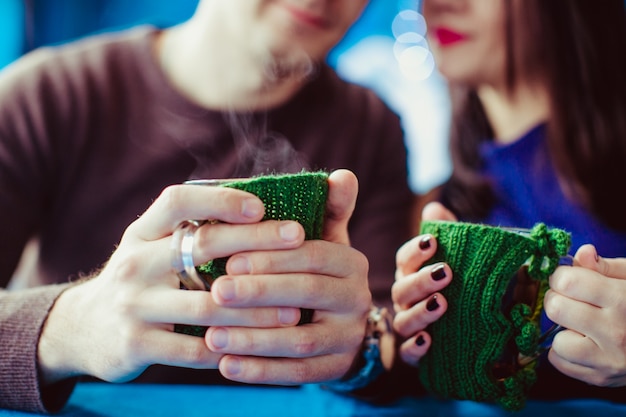 Couple holding knitted coffee cups dressed in sweater