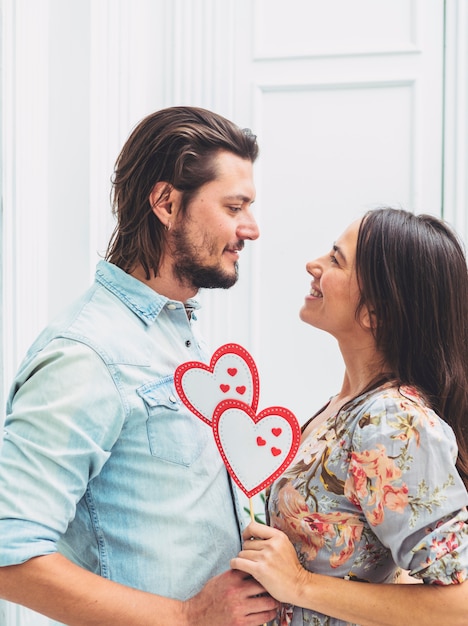 Free photo couple holding paper hearts on wooden stick