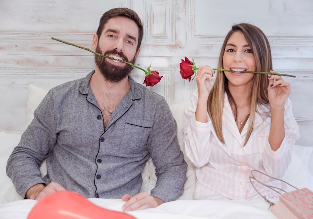 Couple holding red roses in teeth 