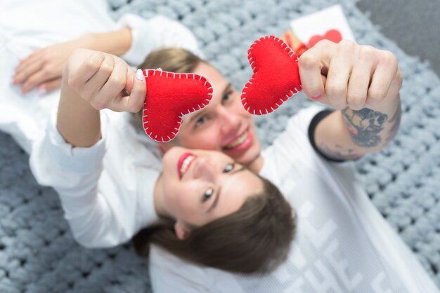 Couple holding red toy hearts in hands 