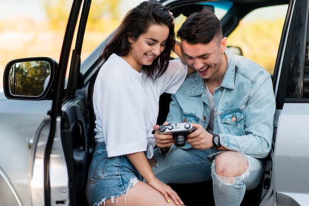 Couple holding a retro camera and looking at photos