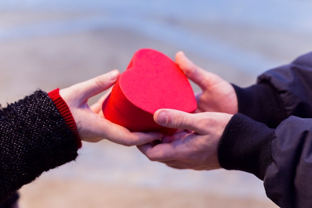 Couple holding small gift box in heart shape 