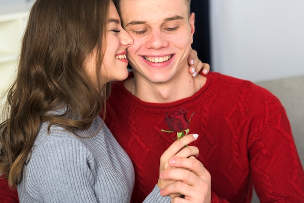 Free photo couple holding small red rose in hands