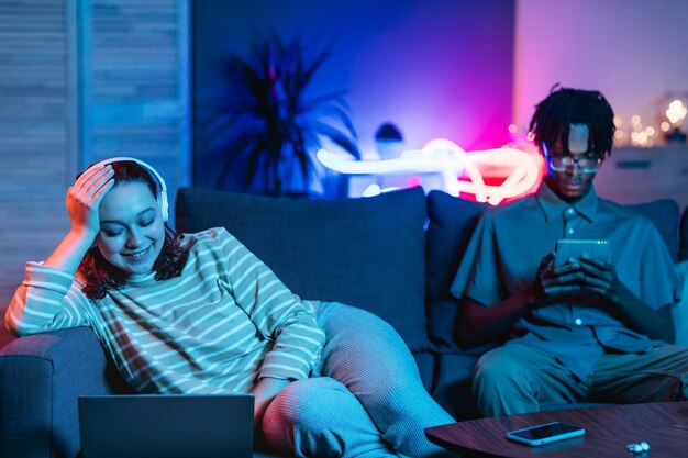 Couple at home together on the couch using modern devices