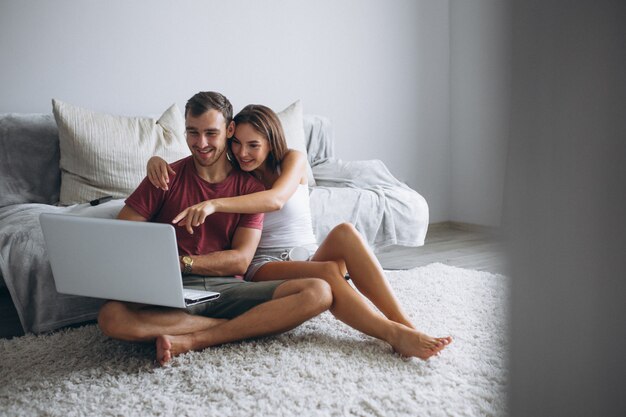 Couple at home together sitting on floor with computer