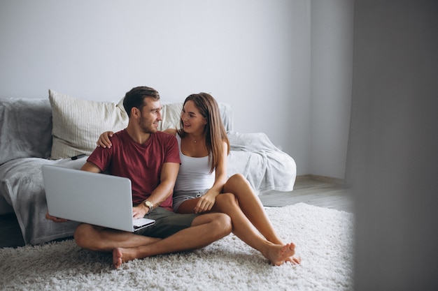 Couple at home together sitting on floor with computer