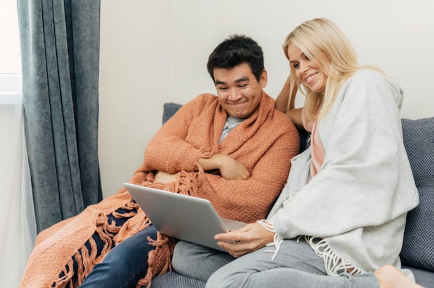 Couple at home together using laptop on the couch