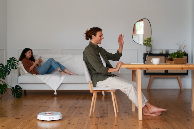 Free photo couple at home with robotic wireless vacuum cleaner