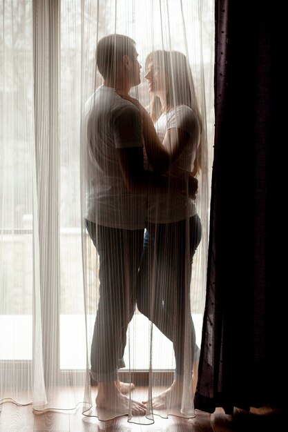 Couple hugging behind a curtain