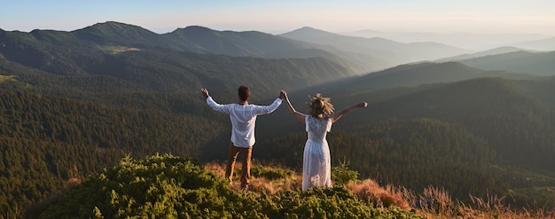 Free photo couple is holding hands on top of mountain