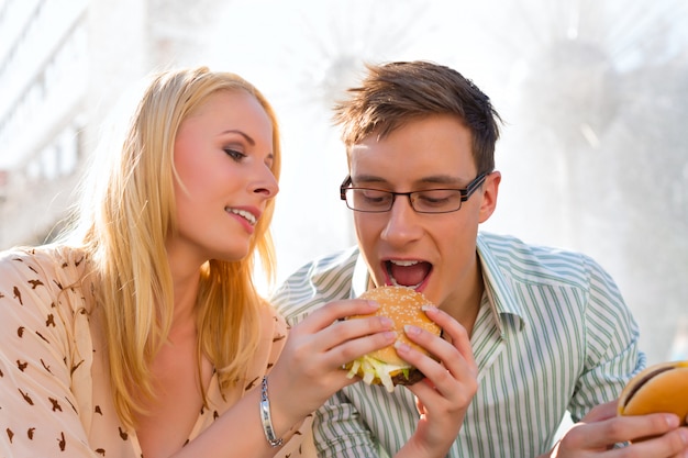 Пара голодна и ест гамбургер в перерыве Premium Фотографии