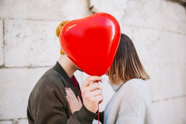 Couple kissing behind balloon