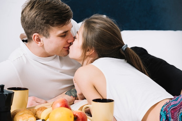 Free photo couple kissing on bed with food