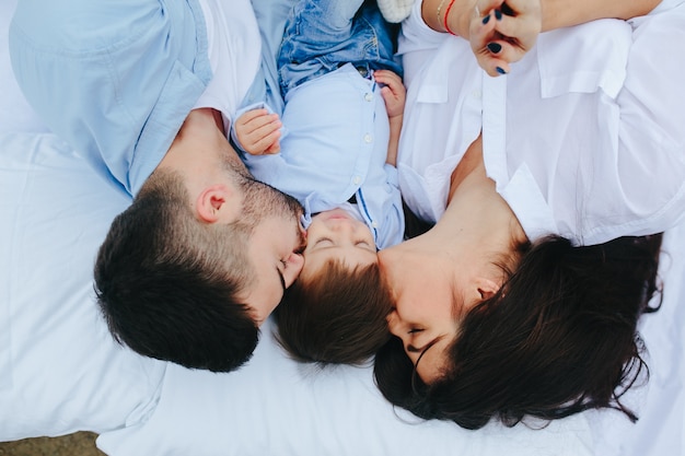 Couple kissing child on bed