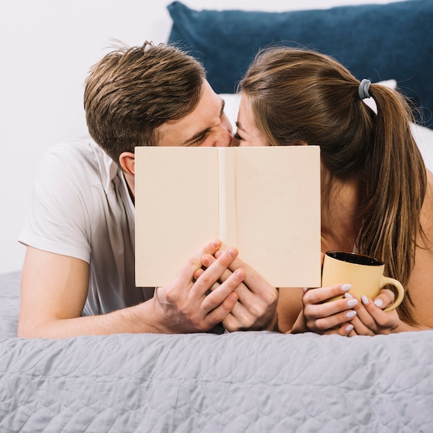 Free photo couple kissing covering faces on bed