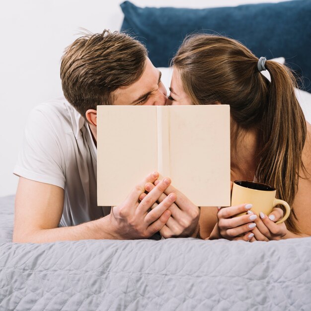 カップルがベッドの上のカバー面にキス