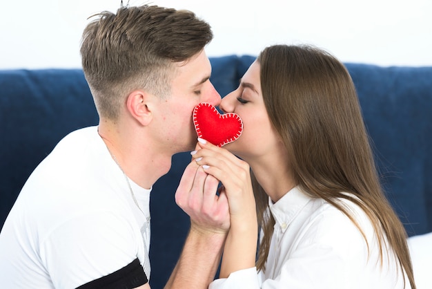 Couple kissing holding small heart in hands 