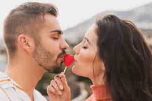 Free photo couple kissing lollipop