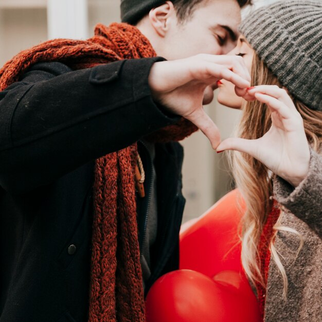 Couple kissing and making heart gesture