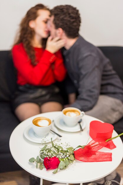 Couple kissing near table with rose and coffee cups