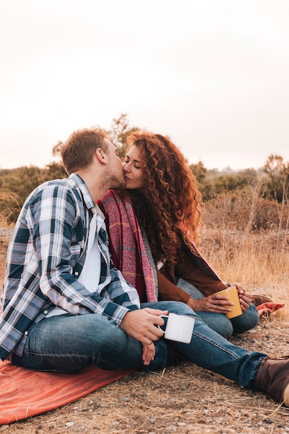 Free photo couple kissing outdoors on a blanket