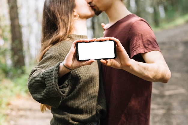 Пара целовать и показывать смартфон шаблон в природе