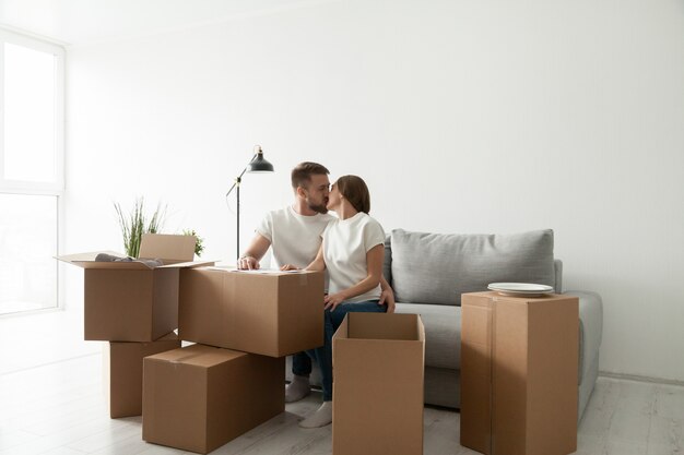 Couple kissing sitting on sofa in living room with boxes
