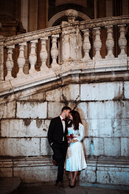 Couple kissing in street leaning on building wall