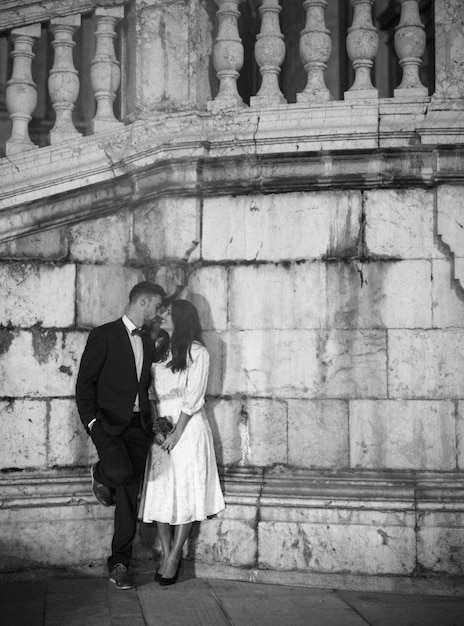 Couple kissing in street leaning on wall 