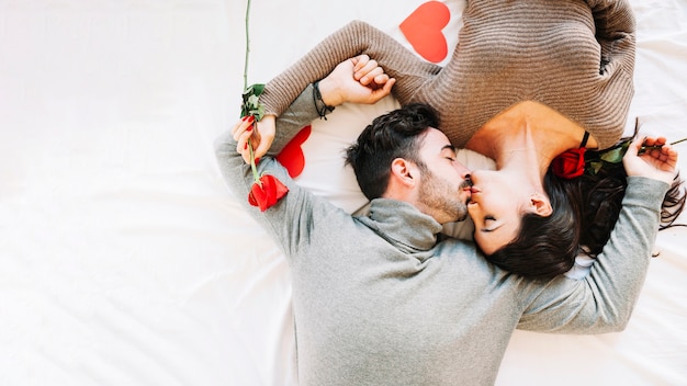 Couple kissing on white sheet