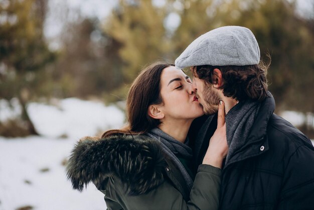 Couple kissing in winter park having fun