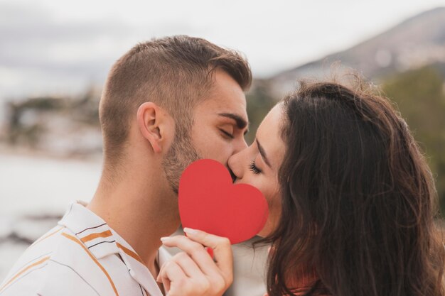 カップルが紙のハートの形でキス