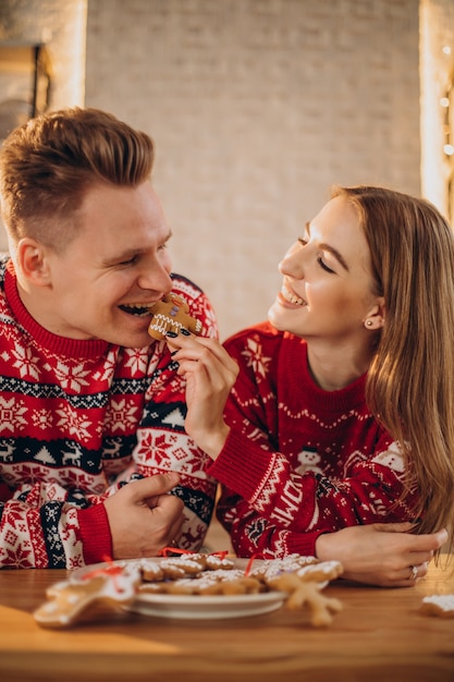 Couple at kitchen eating christmas cookie man