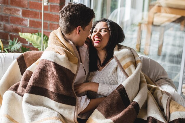 Couple laughing covered with a blanket