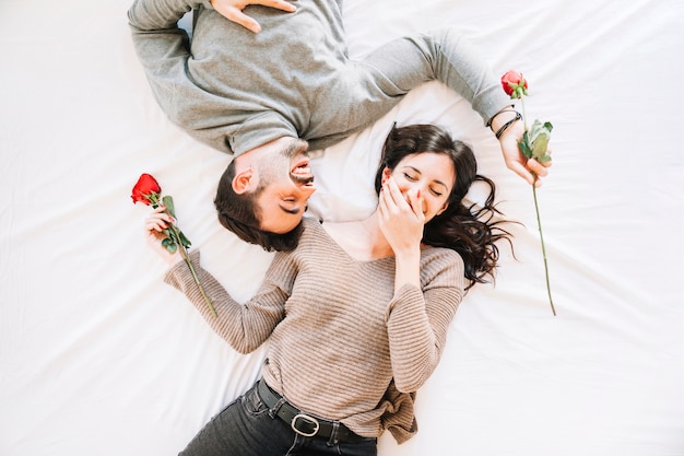 Couple laughing on white sheet