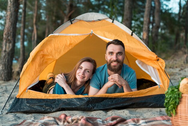 Couple laying down in the tent looking at camera