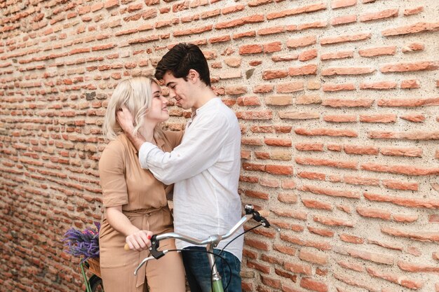 Couple leaning in for a kiss with bicycle and copy space