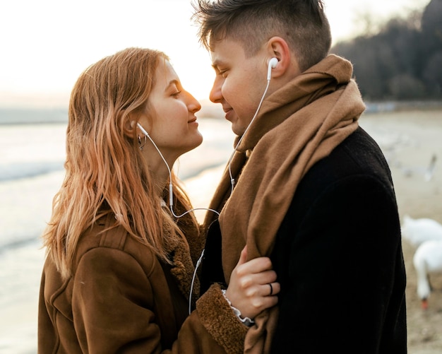 Couple listening to music on earphones on the beach in winter