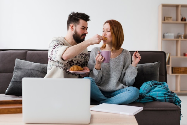 Couple in living room eating croissants