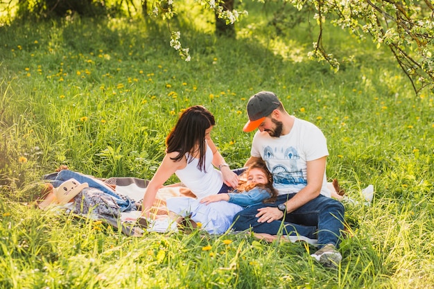 公園で緑の草の上に座っている娘を見てカップル