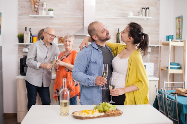 Free photo couple looking at each other in kitchen during family brunch. man holding glass of wine. appetizer with various cheese.