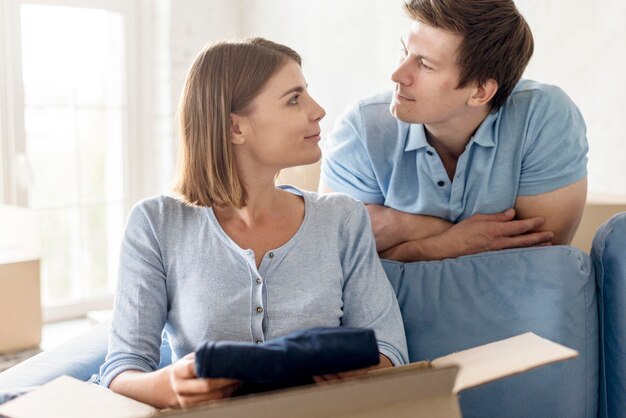 Couple looking at each other while packing box to move house