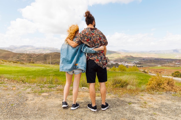 Couple looking into distance from hilltop